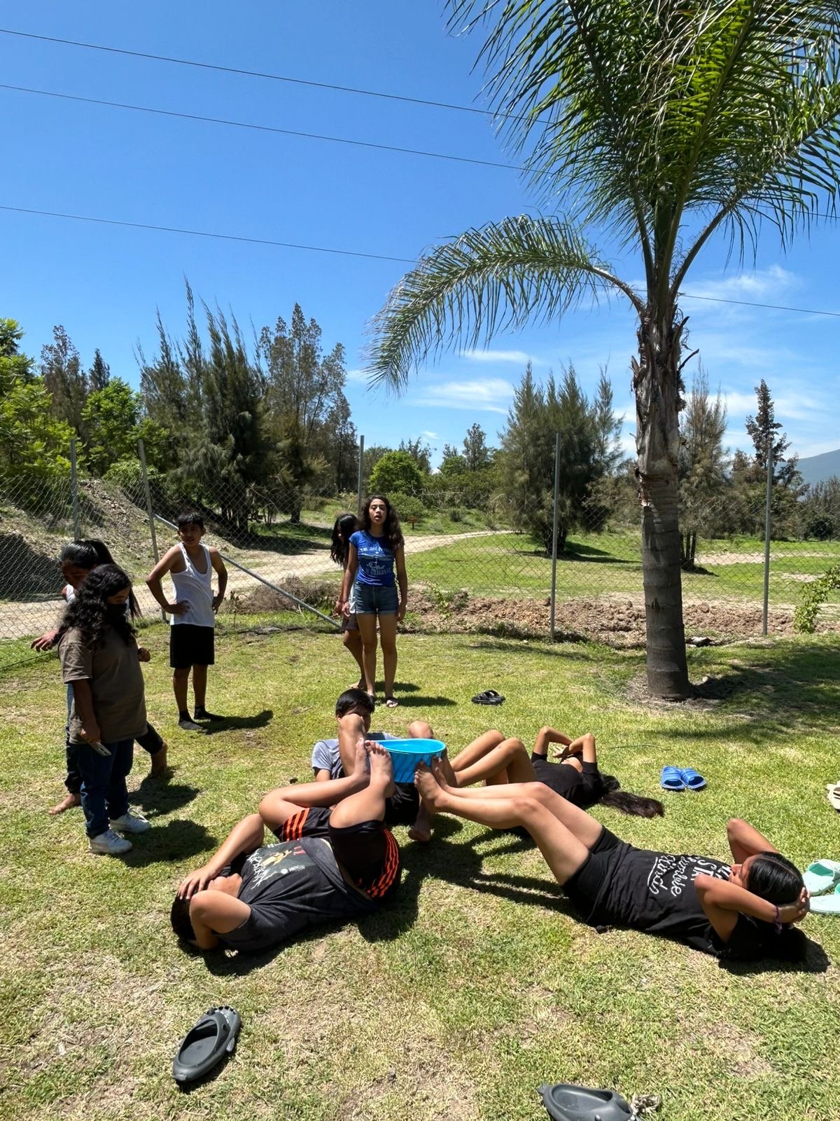 Grupo de jóvenes en dinámica junto a la cancha de voleibol